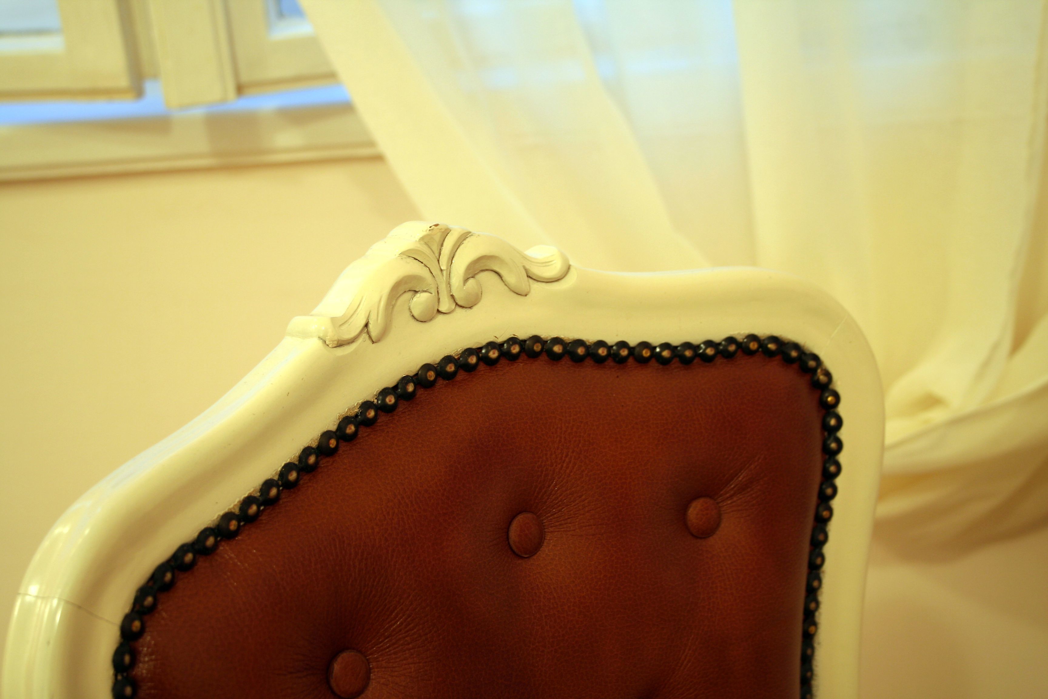 Primer plano de una silla con reposacabezas tapizado en marrón y detalles decorativos.