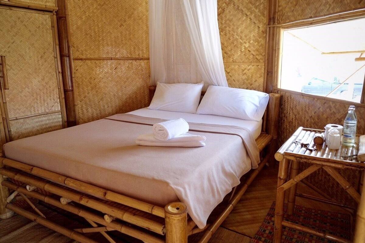 Una cama individual con dosel, ropa blanca y una mesita con artículos de aseo.