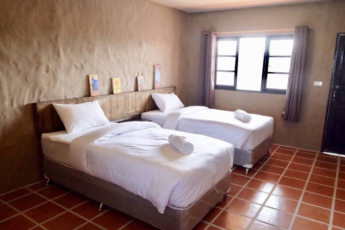 Una habitación con dos camas, una ventana con cortinas y una puerta.