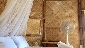 A room with a bed, a mosquito net, a fan, and a window. - Korawan Garden View (Hua Hin)