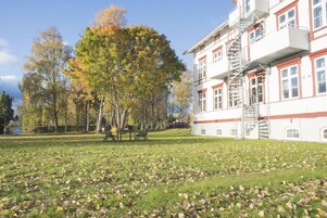 A building with a white facade and red trim, a fire escape, and a grassy area with scattered leaves.