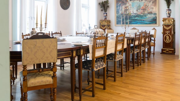 Comedor con una larga mesa de madera, sillas tapizadas y una araña.