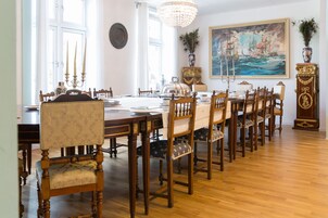 A dining room with a long wooden table, upholstered chairs, and a chandelier.