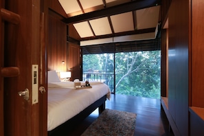 A bedroom with a large bed, wooden walls, a view of trees, and a balcony. - Vanilla Hill (Hang Dong)