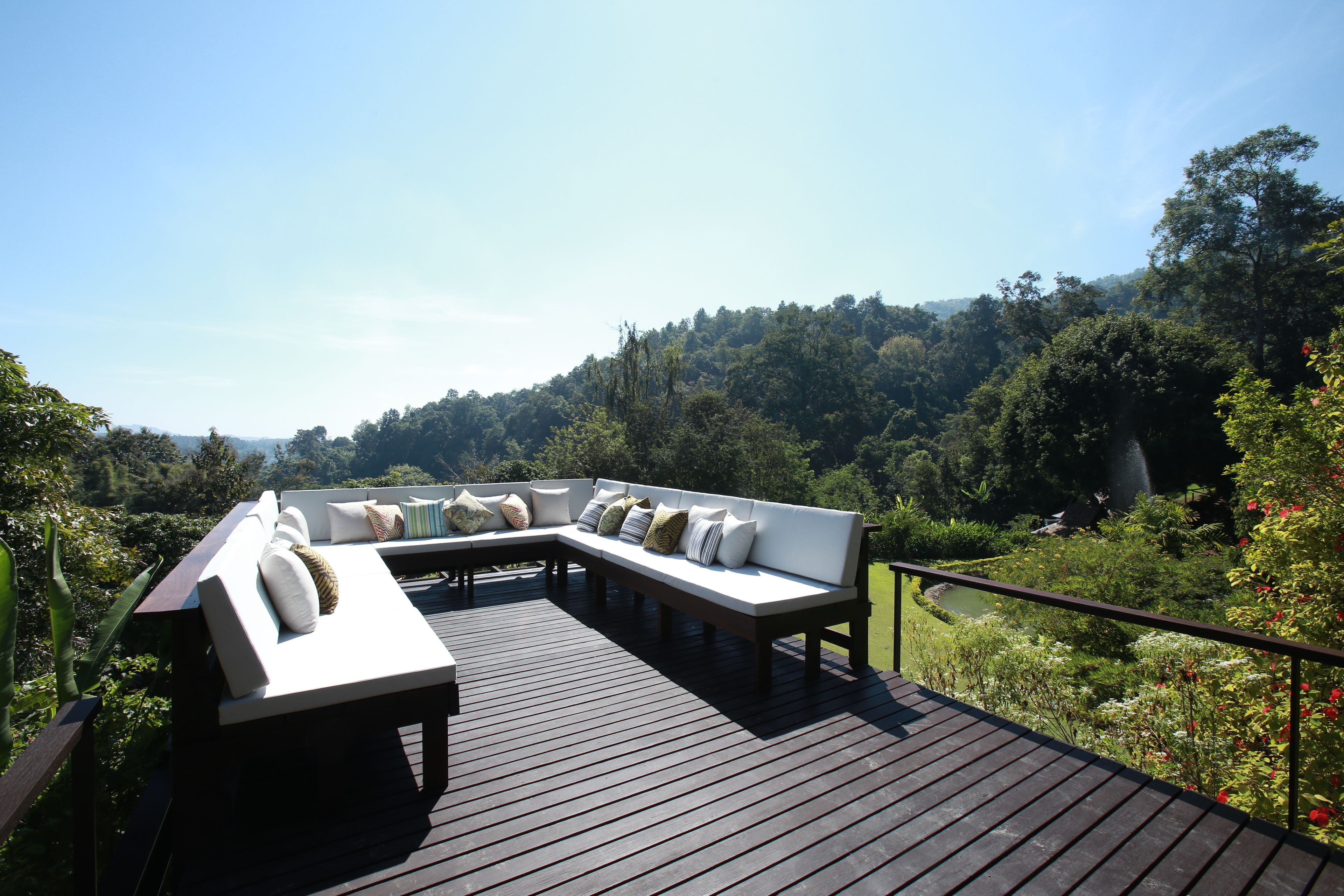 A wooden deck with a white sectional sofa and a small table.