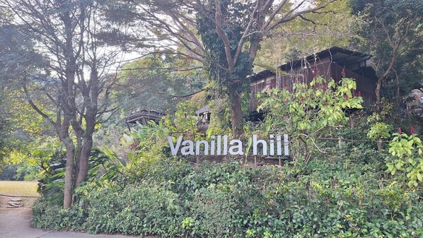 A sign for 'Vanilla Hill' amidst lush greenery and trees. - Vanilla Hill (Hang Dong)