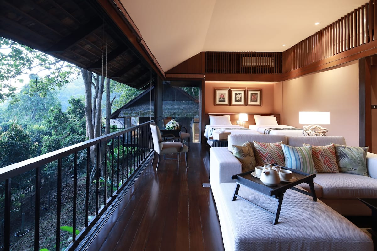 A spacious balcony with wooden railings, a sofa set, and a dining table with teapots.