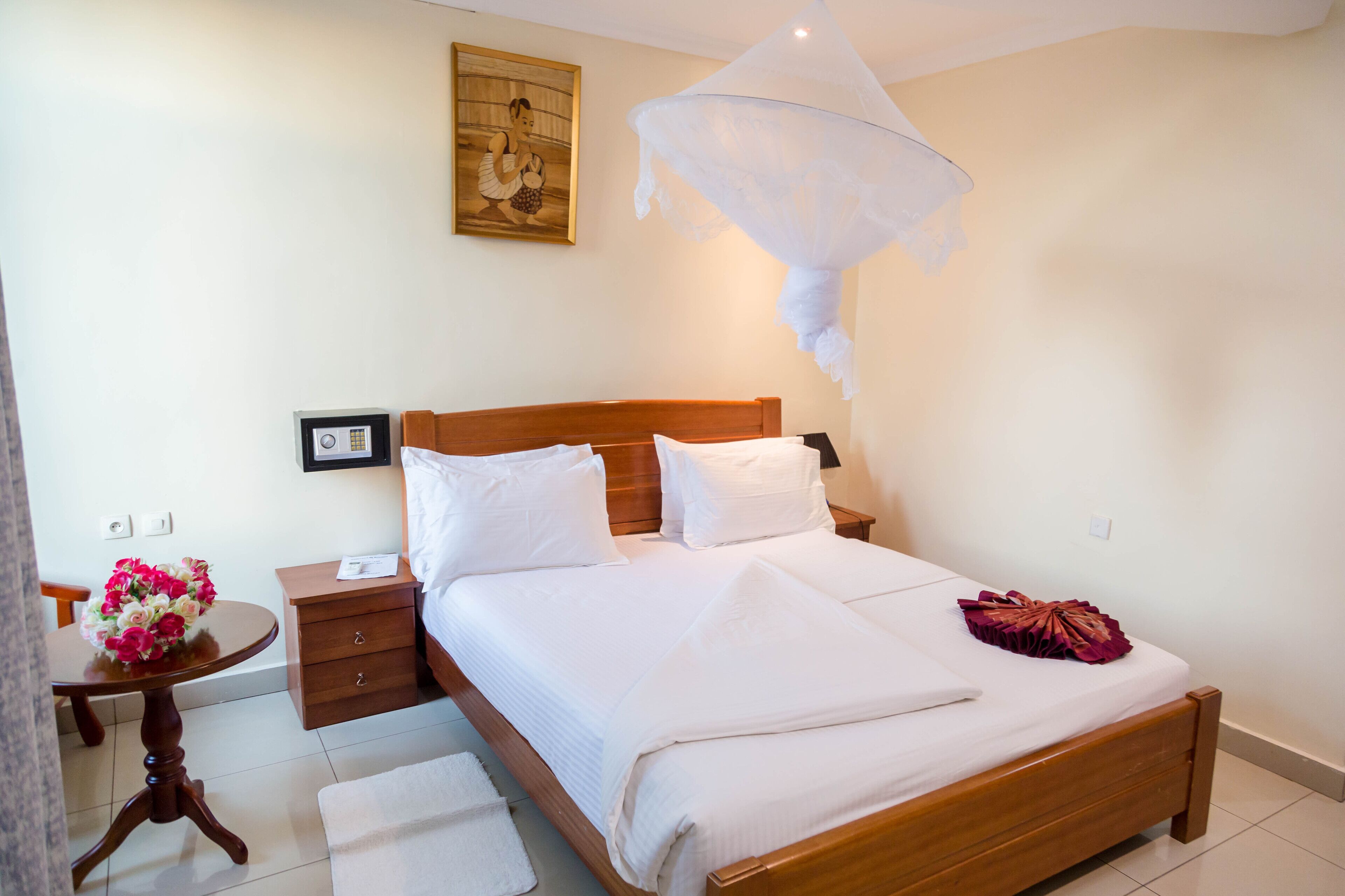 A neatly made bed with white linens, a wooden headboard, and a decorative pillow.