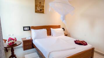 A neatly made bed with white linens, a wooden headboard, and a decorative pillow.