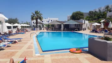 Relax by the pool surrounded by lounge chairs and umbrellas on a tiled deck.