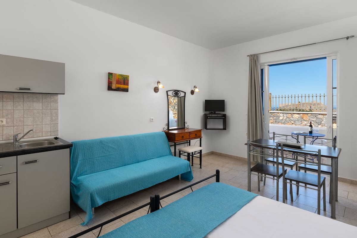 Habitación con kitchenette, un sofá, una mesa de comedor con sillas, un televisor y vistas al exterior.