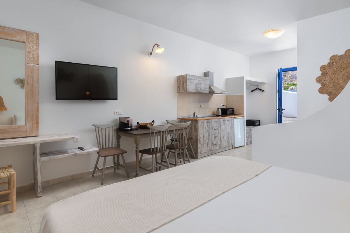 Una cocina moderna con televisor de pantalla plana, sillas de madera y una barra desayunadora.