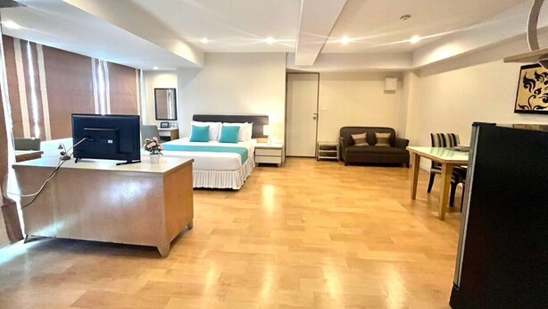 Ein Hotelzimmer mit Bett, Schreibtisch, Fernseher und einer Essecke mit Tisch und Stühlen.