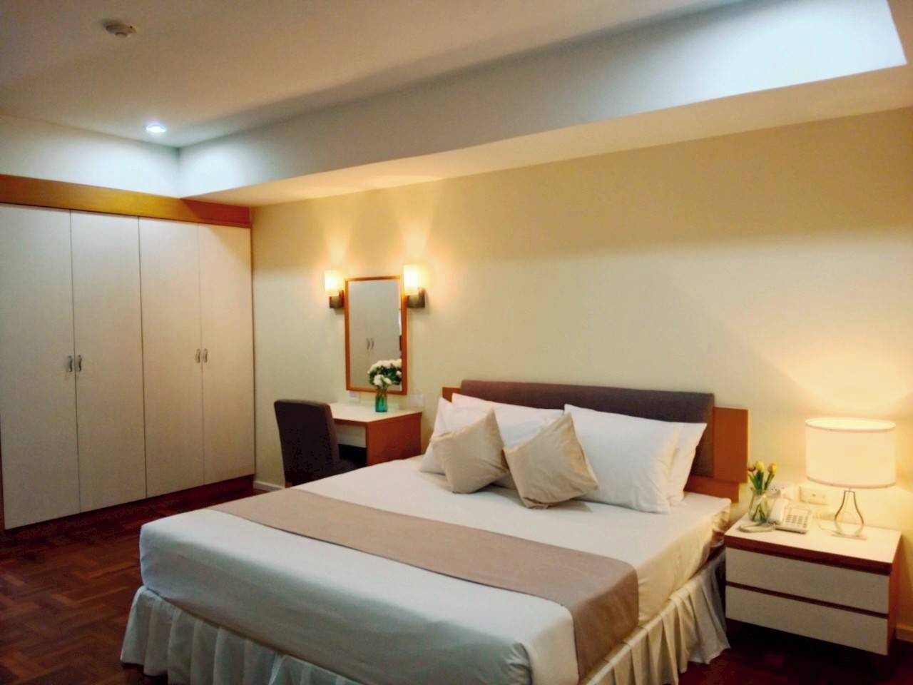 Une chambre d’hôtel comprenant un lit, une table de chevet, une lampe, un bureau, une chaise et une armoire.