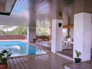An indoor swimming pool with tiled flooring, a wooden ceiling, and potted plants. - Sky Place Serviced Apartment (Bangkok)