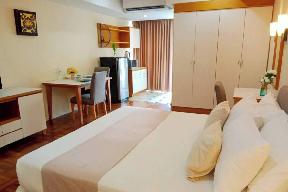 A hotel room with a bed, a desk, a chair, a wardrobe, and a television.