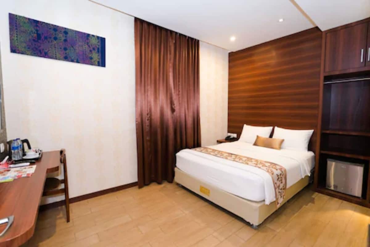 A hotel room with a bed, a desk, and a chair.