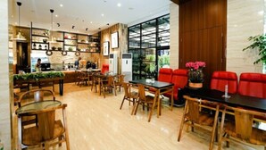 A modern restaurant with wooden furniture, a bar area, and a large window providing a view of the outdoors. - The Batik Hotel (Medan)