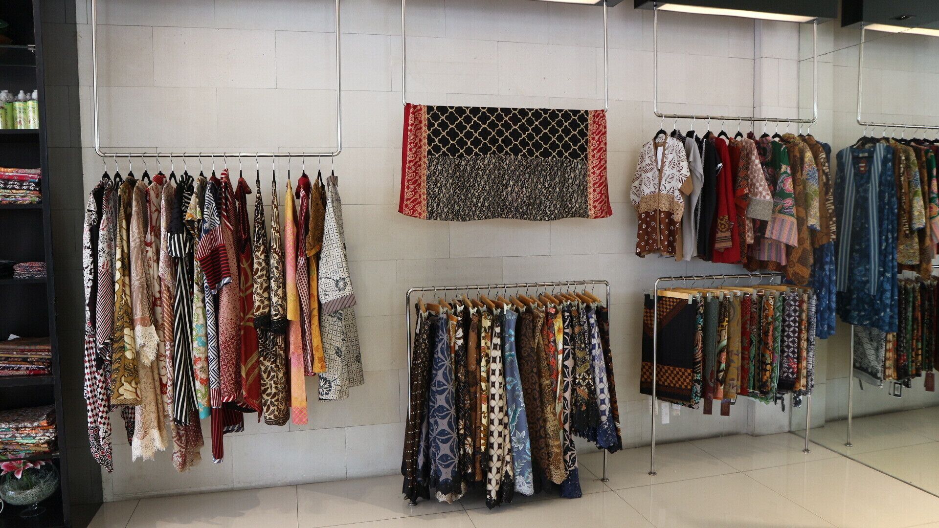 Uma loja de roupas com araras cheias de cachecóis e tecidos estampados.