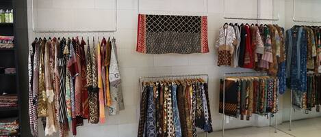 Uma loja de roupas com araras cheias de cachecóis e tecidos estampados.