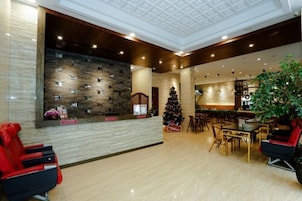 Un hall con pared de piedra, un árbol de Navidad y un mostrador de recepción.