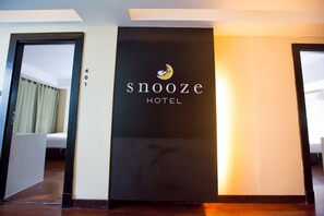 L’entrée d’un hôtel, avec une enseigne indiquant « SNOOZE HOTEL » et le numéro « 401 » au-dessus.