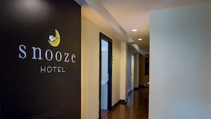 Een gang met een bordje voor 'Snooze Hotel' en een deur die naar een andere kamer leidt.