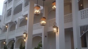 Un hôtel à plusieurs étages doté de balcons, d’un éclairage extérieur et d’un escalier menant à l’entrée.