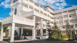 Un hôtel à plusieurs étages, doté d’une façade blanche, de balcons et d’un espace d’entrée abrité.