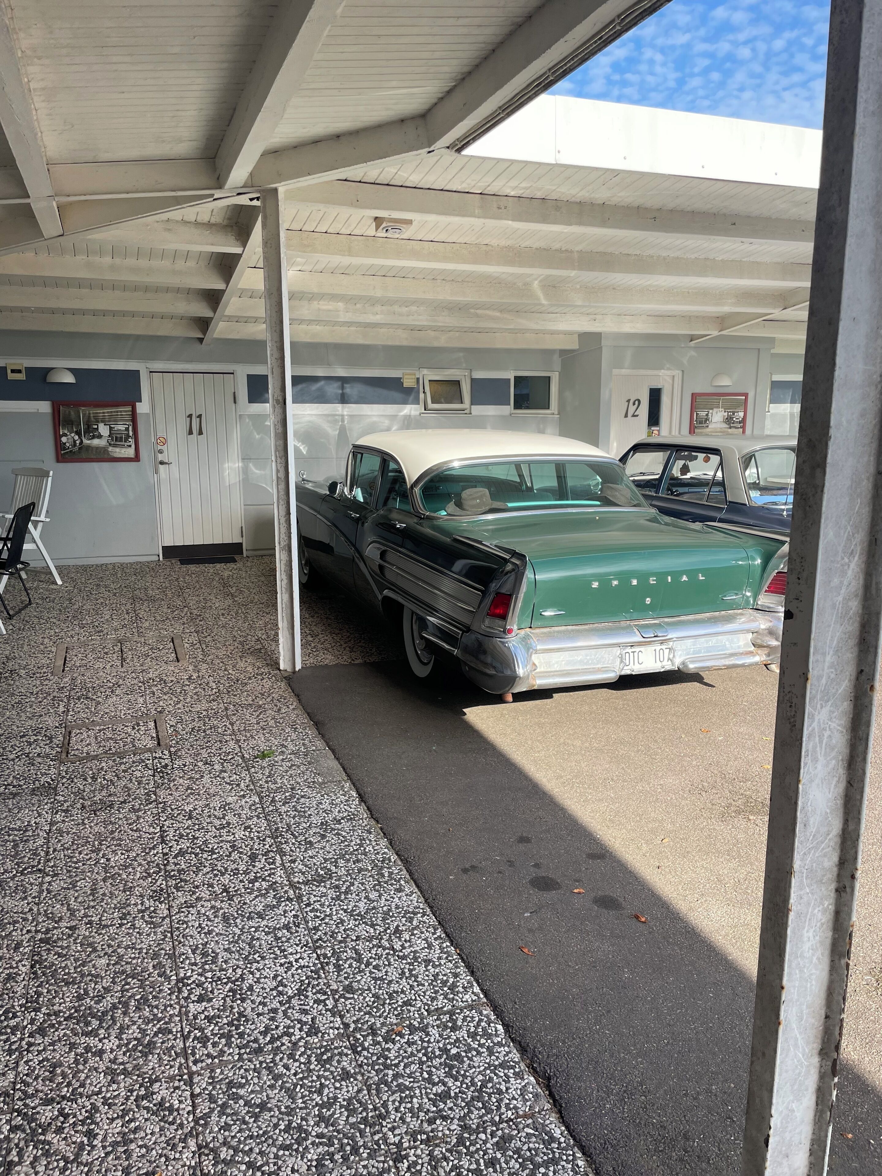 Ett parkeringsgarage med en grön och vit bil parkerad under ett tak.