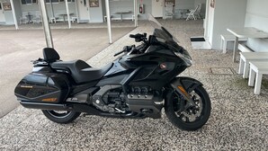 A black motorcycle parked in a covered outdoor area with white tables and chairs. - Fleninge Classic Motel (Fleninge)