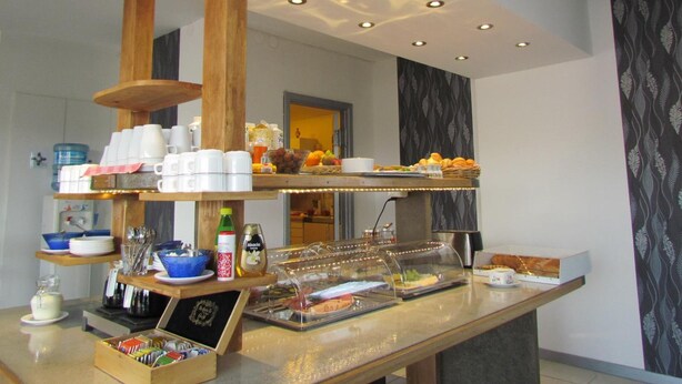 A buffet setup with various food items, utensils, and condiments. - Fleninge Classic Motel (Fleninge)