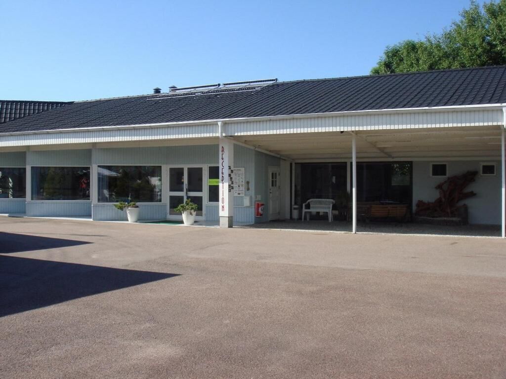 En byggnad med en överbyggd entré, stora fönster och krukväxter.