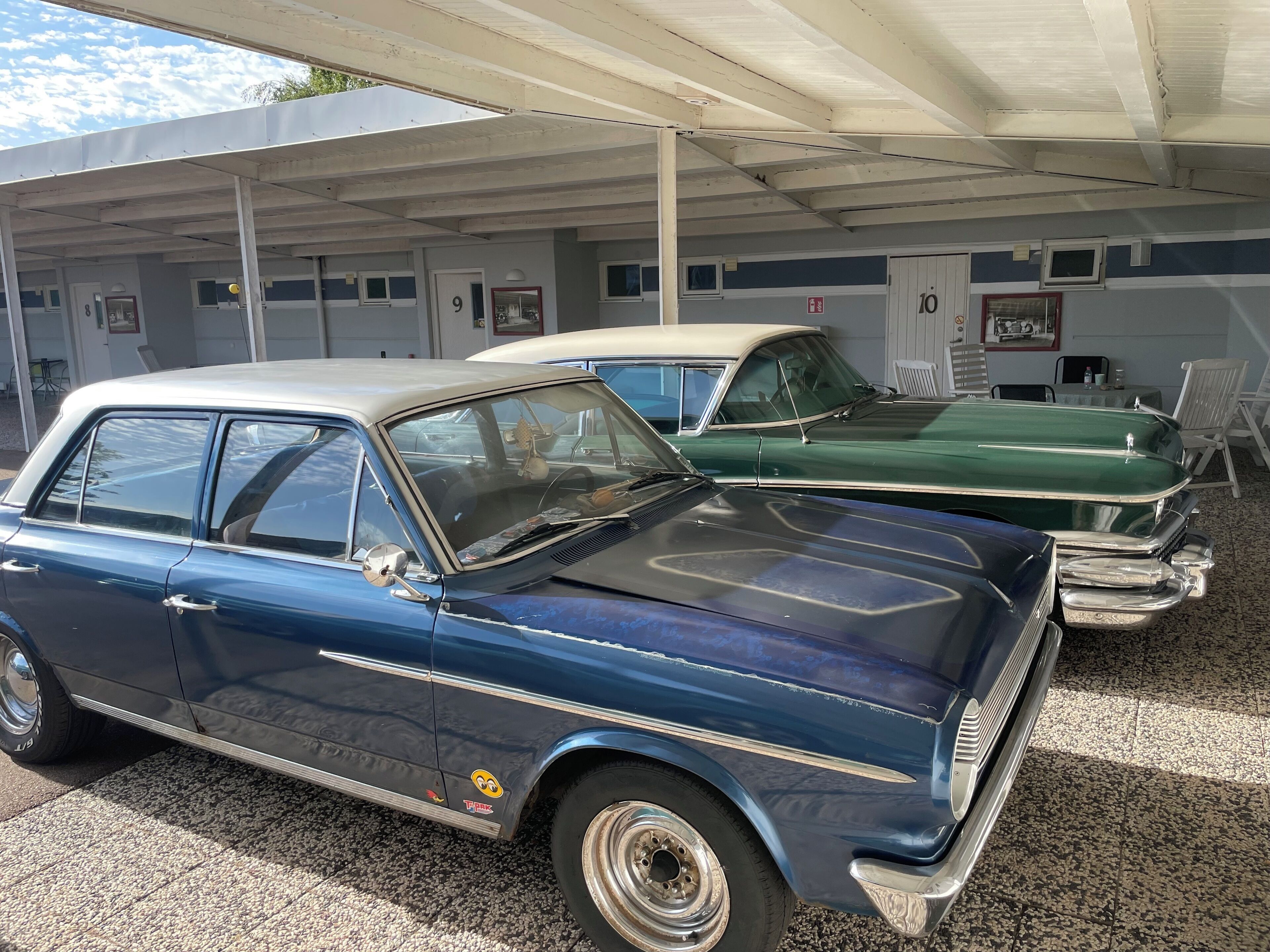 A parking garage with two vintage cars parked under a covered area.