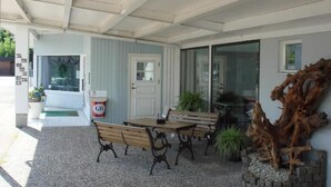 An outdoor patio with a covered seating area, a door, and a large piece of driftwood. - Fleninge Classic Motel (Fleninge)