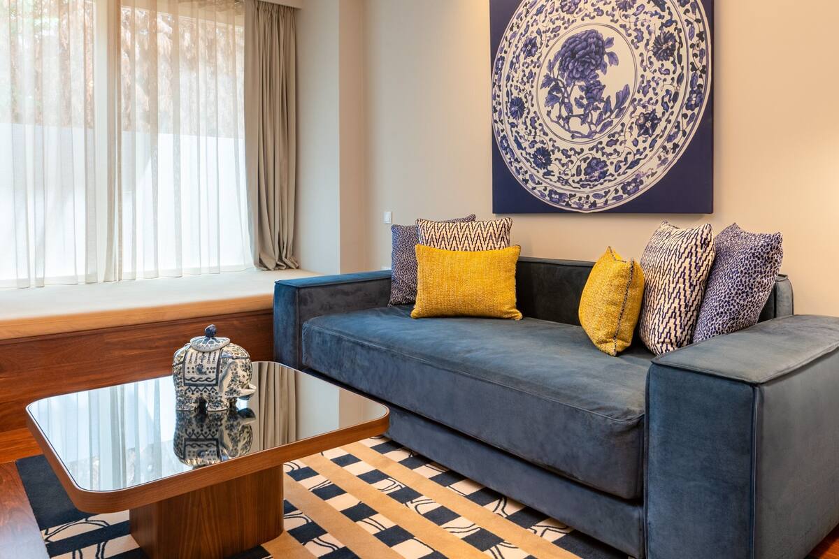 A living room with a sofa, patterned cushions, a coffee table, and a decorative plate on the wall.