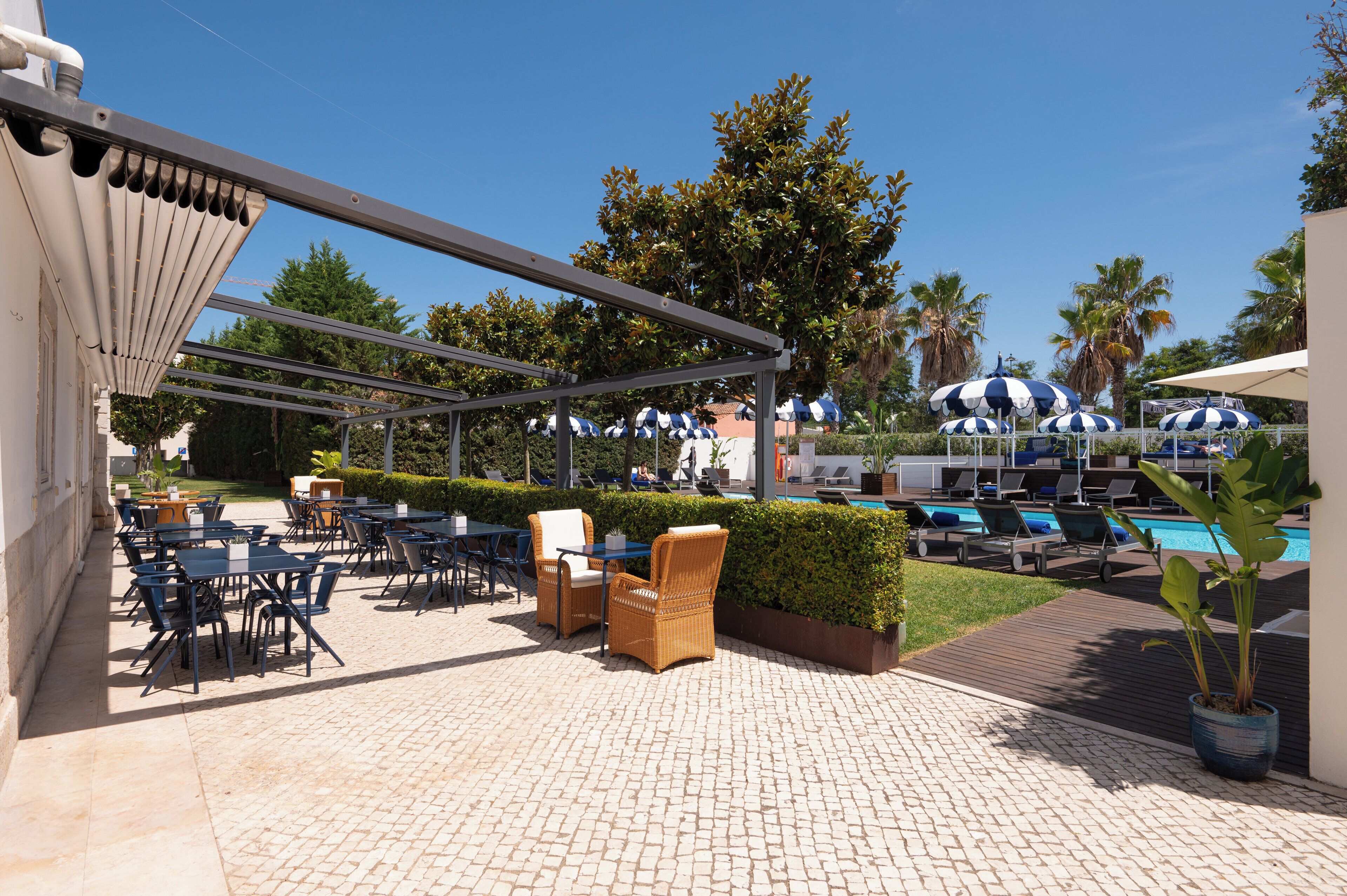 Un espace extérieur aménagé en terrasse, avec des tables et des chaises, une piscine et des parasols.