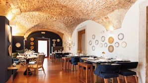 Un restaurante con techo de piedra rústica, mesas de madera y sillas tapizadas en azul.
