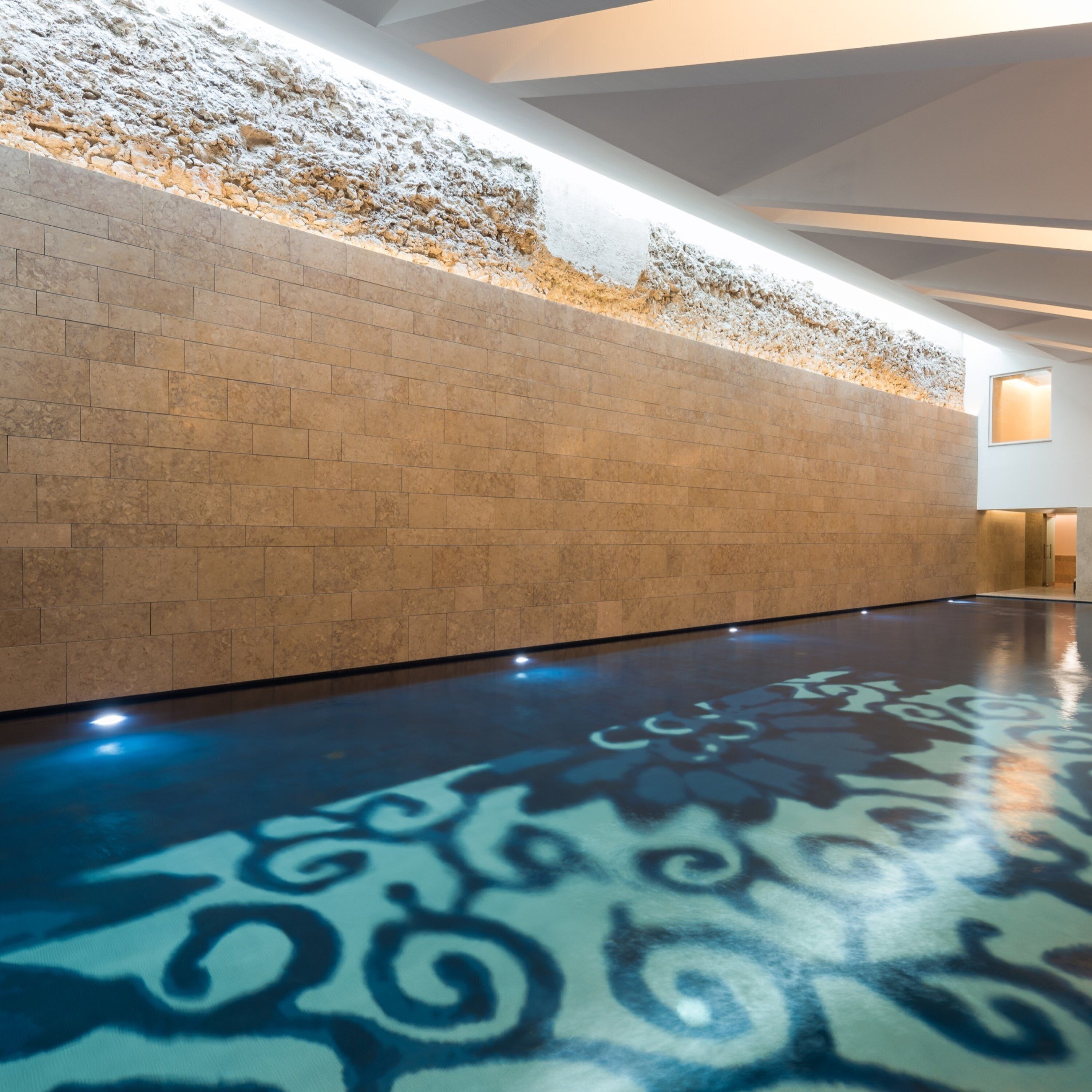 A hallway with a patterned floor and a textured wall.