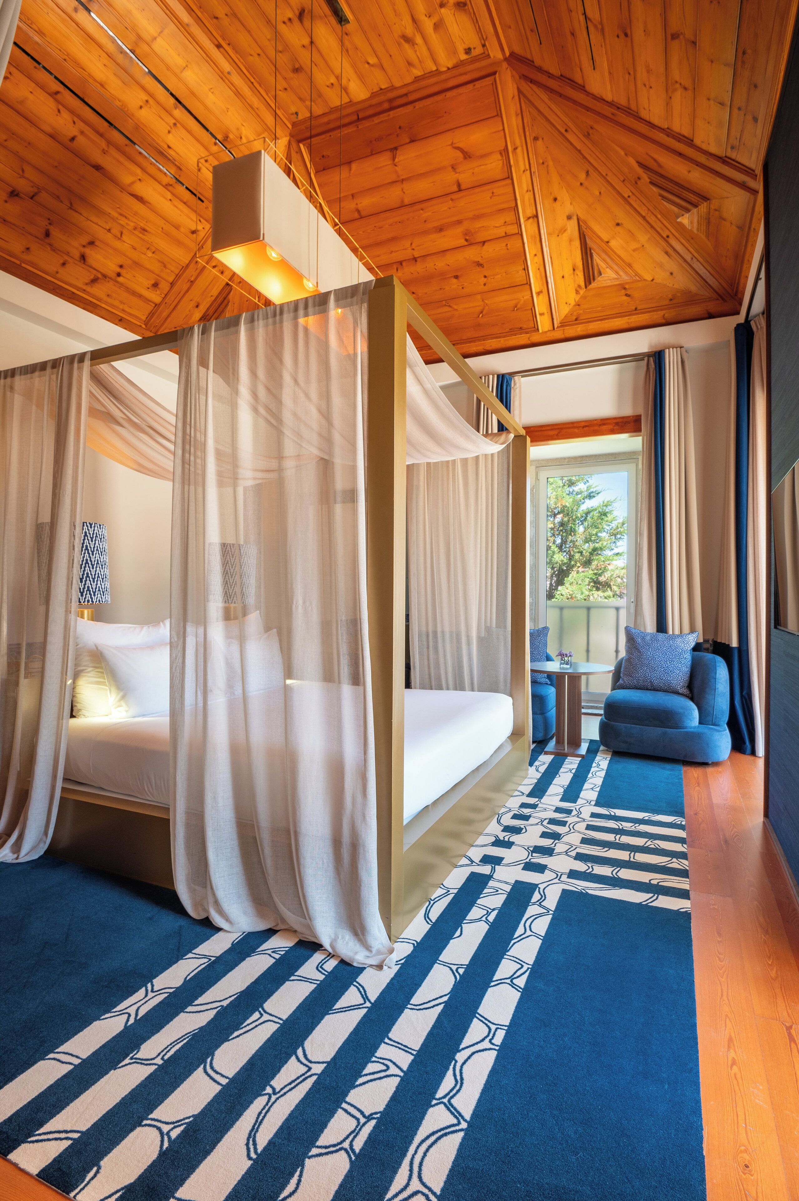 Un dormitorio con una cama con dosel, una mesita y un sofá azul.
