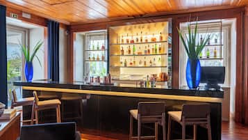 Een bar met houten plafond, flessenkasten en barstoelen.