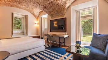 Una habitación de hotel con cama, escritorio con silla, televisor y sofá.
