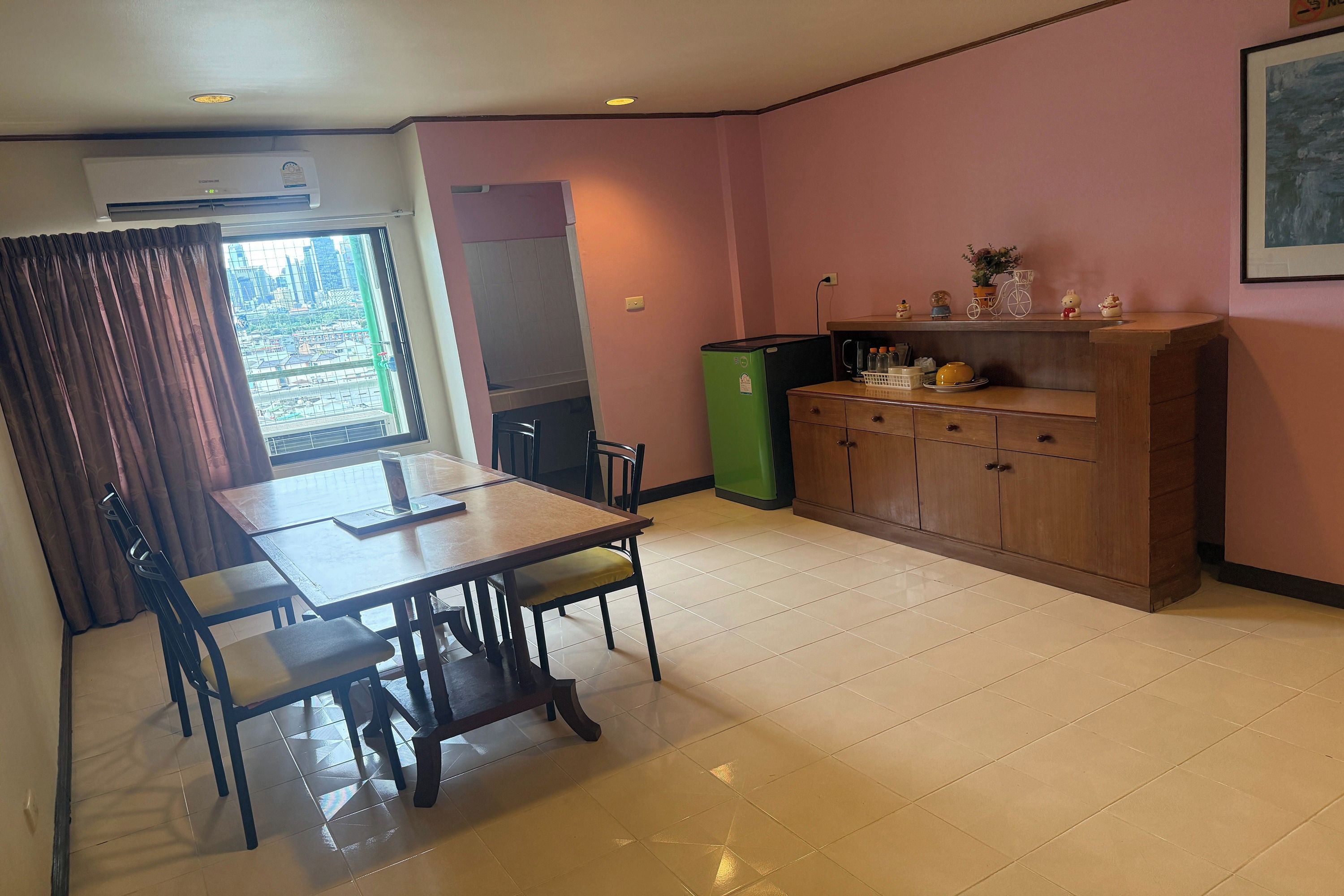 A dining area with a table and chairs, a refrigerator, a cabinet, and a window with curtains.