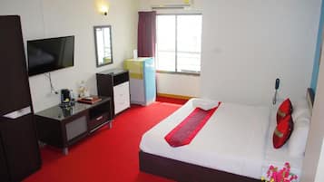 A hotel room with a bed, a desk, a television, a wardrobe, and a window with curtains.