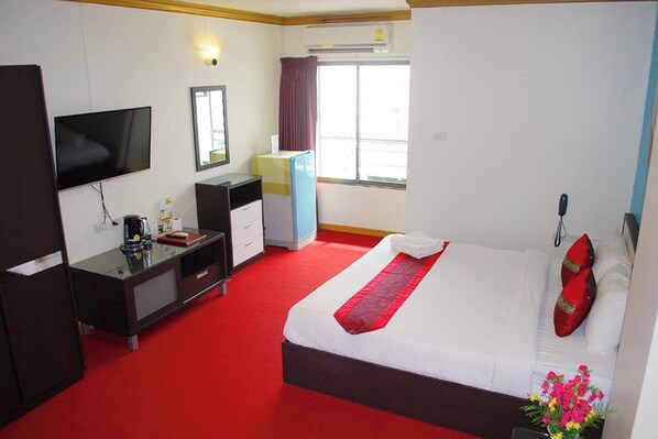 A hotel room with a bed, a desk, a television, a wardrobe, and a window with curtains. - Witchuwan Sport & Spa Apartel (Bangkok)