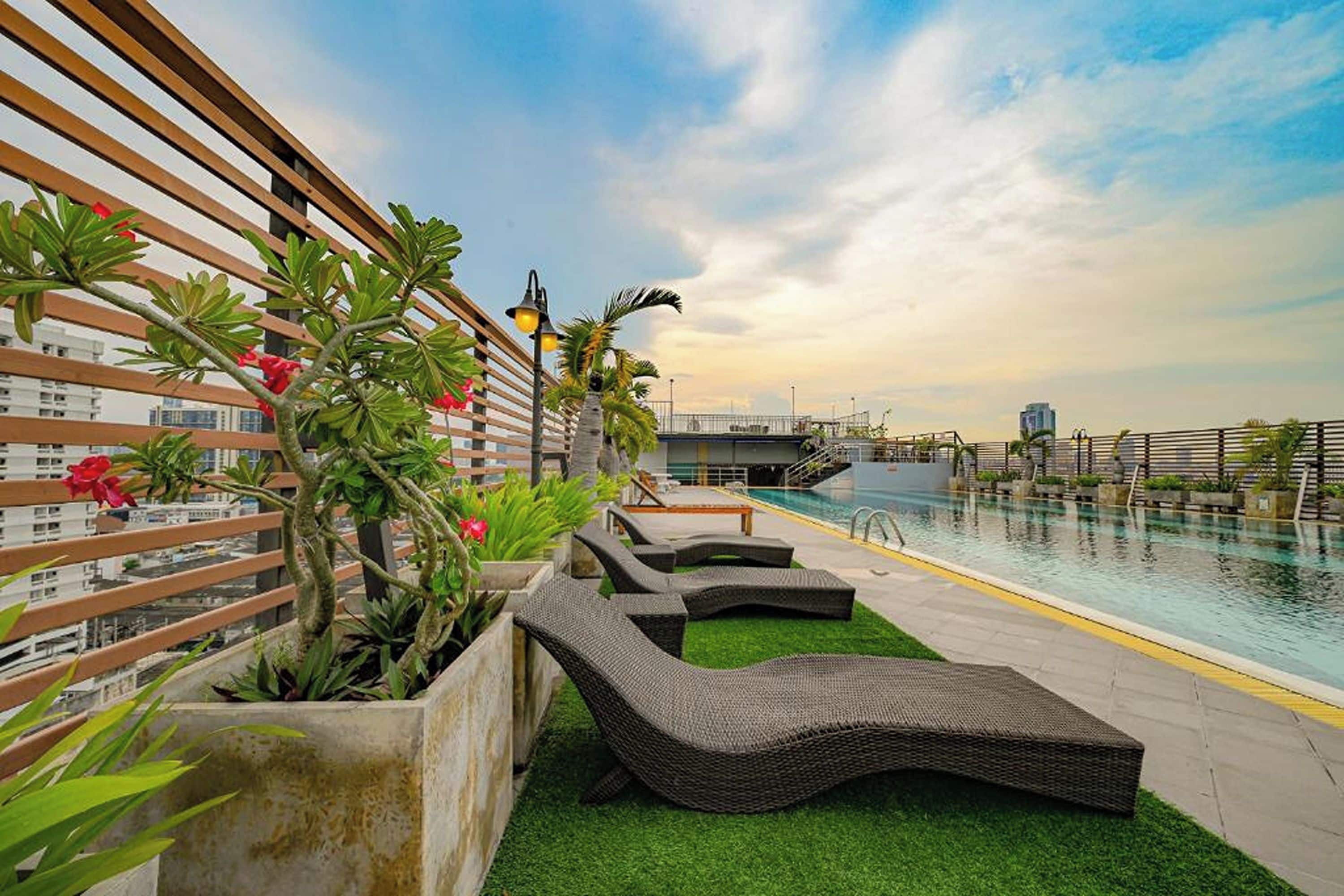A rooftop pool area with lounge chairs, a pool, and a view of the city skyline.