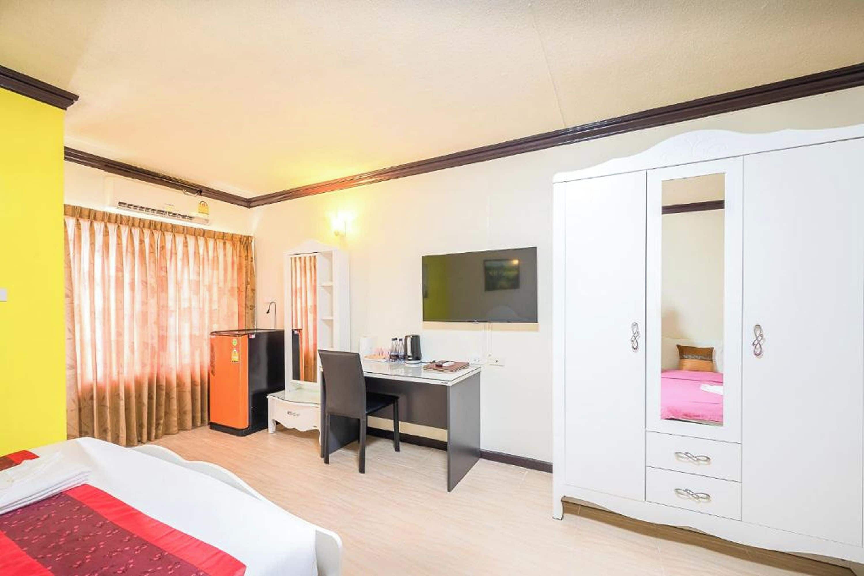 A hotel room with a bed, a desk, a wardrobe, a television, and a window with curtains.