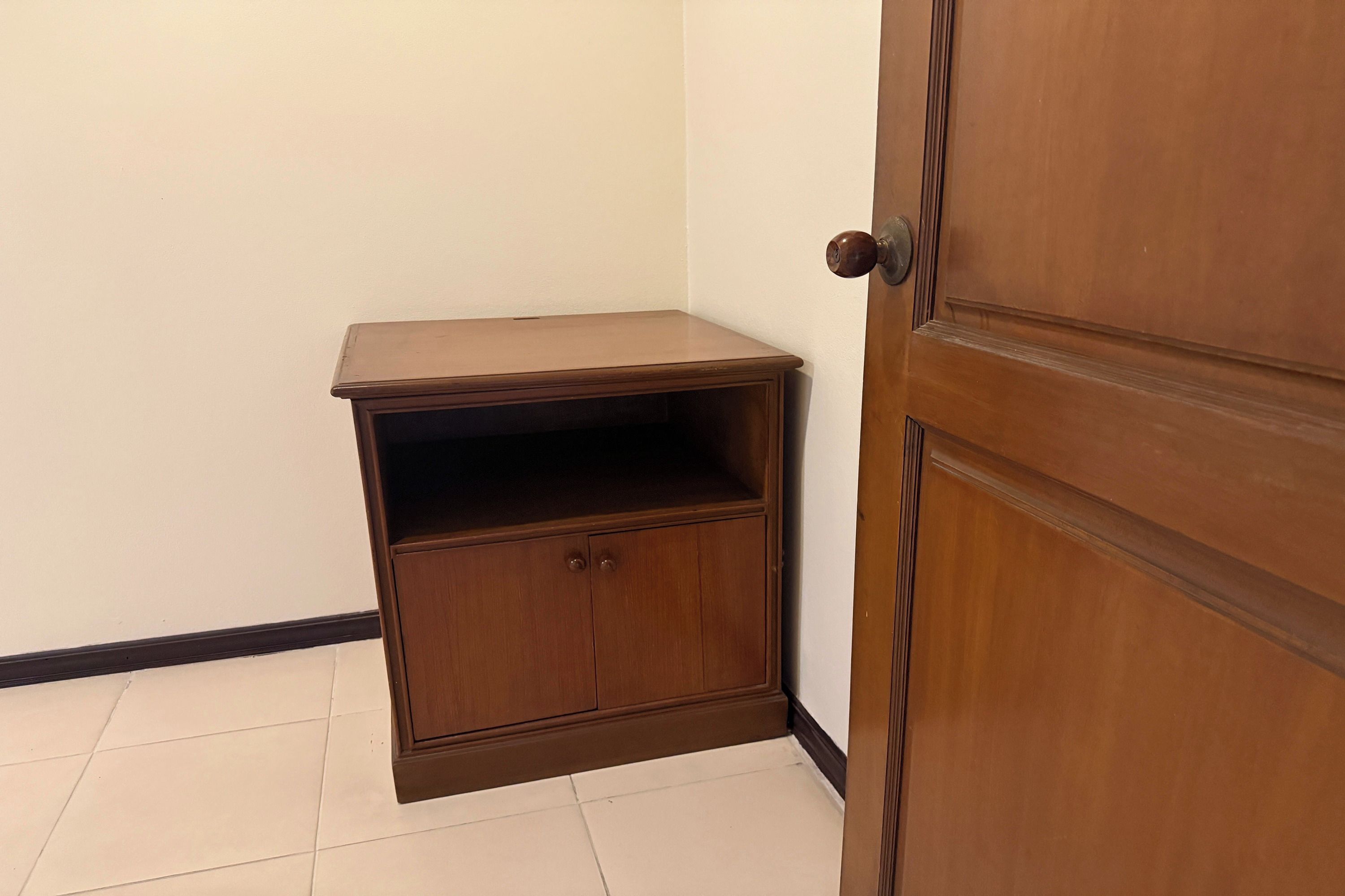 Une pièce d’angle avec un meuble en bois et une porte.