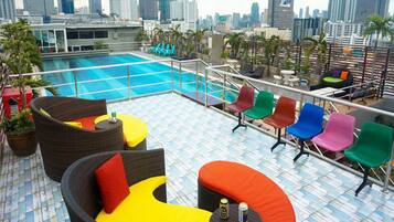 Relax on the rooftop terrace with a panoramic view of the city skyline, surrounded by a swimming pool and comfortable seating options.