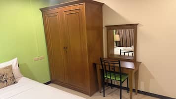 Una habitación con cama, escritorio, silla, armario y espejo.